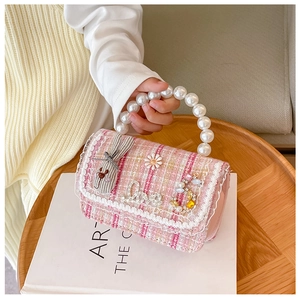 Detail of pink tweed girl bag with pearl handle, floral charms and rhinestone Love text