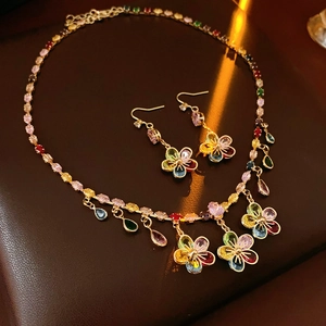 Detail of luxury gold flower jewelry set with colorful stones and drop pendants