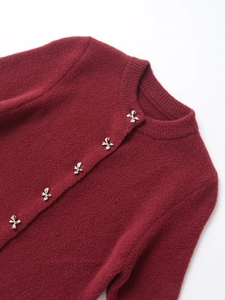 Detail of burgundy knit cardigan featuring silver bow buttons and soft mohair texture