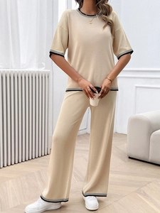 Détail d'un ensemble beige en maille avec haut à manches courtes et pantalon large orné