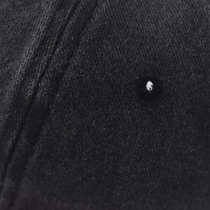 Macro detail of the breathable eyelet and washed cotton texture on the black baseball cap