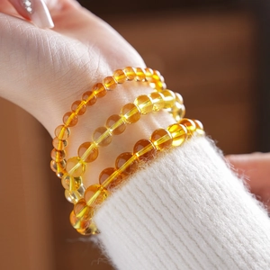 Macro shot of yellow citrine multi-layer beaded bracelet worn on a white knitted sleeve