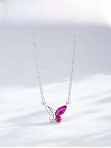 Vue macro du pendentif papillon en argent S925 avec gemmes magenta sur fond de soie blanche