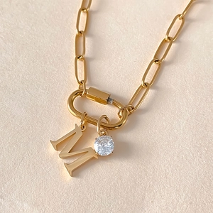 Nahaufnahme Goldkette mit Buchstaben-M-Anhänger und funkelndem Zirkonia-Kristall