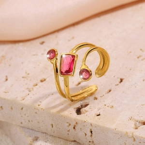 Detail of adjustable gold ring with pink gems on a stone with soft pink fabric background