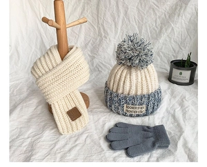 Detail view of beige and blue knitted winter set with hat, scarf and gloves set