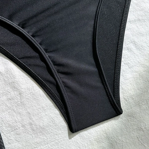 Detailopname van zwart bikinibroekje met nauwkeurig dubbelstiksel en de textuur van de stof