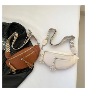 Macro shot of brown and cream textured leather waist bags with decorative tassel zippers