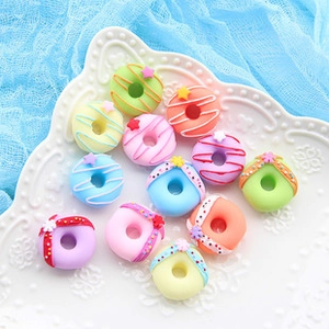 Flat lay of miniature resin donut charms in pastel colors on a white textured plate