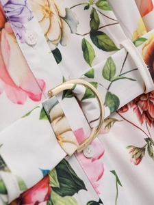 Détail d'une robe midi fleurie avec boutons blancs et ceinture à boucle dorée en D