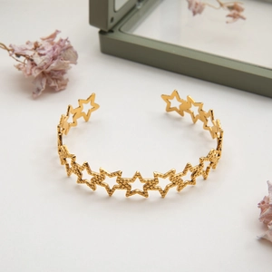 Detail of gold hollow star cuff bracelet with hammered texture on a gift jewelry box