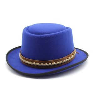 Detail of royal blue wool felt boater hat with brown braided band and black piped edge