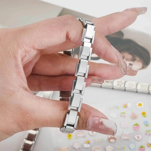 Bracelet italien modulaire poli en acier inoxydable argenté tenu en main avec détails