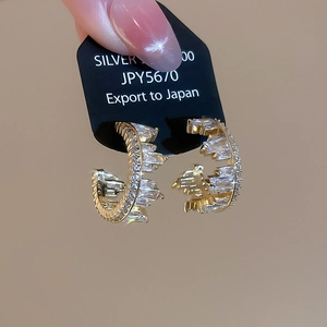 Macro view of C-shaped gold-plated S925 silver earrings with baguette-cut zircon pavé