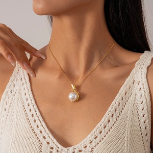 Detail of elegant gold pearl necklace with zircon-encrusted clasp worn by a model