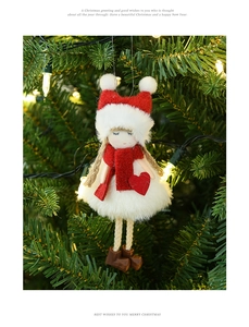 Close-up of plush Christmas girl doll ornament hanging on a festive tree with warm lights