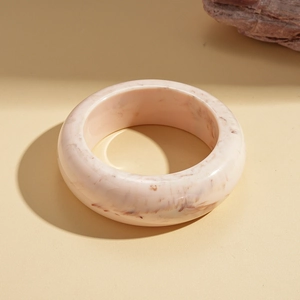 Detailed macro view of pink marble resin bangle on a minimalist warm beige background