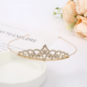 Detailed close-up of golden bridal crown with sparkling rhinestones on white ceramic