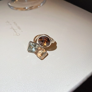 Macro shot of silver ring featuring square and oval gemstones in retro geometric style