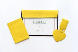 Flat lay of yellow faux leather travel set with passport cover and heart luggage tag