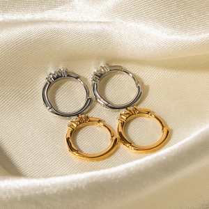 Eleganti cerchi in oro e argento con tre perle su sfondo di raso beige chiaro