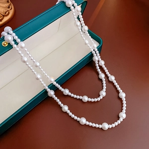 Detailed macro view of elegant double-layered faux pearl necklace over a green jewelry box
