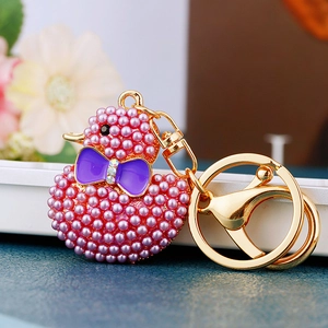 Macro shot of pink pearl-inlaid duck keychain with purple bow and golden lobster clasp