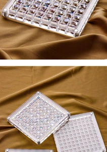 Macro shot of clear acrylic nail art organizer tray with colorful square rhinestones