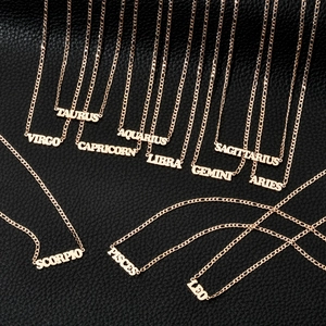 Detailed flat lay of 18K gold-plated zodiac name necklaces on black leather background
