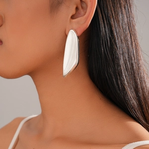 Close-up of minimalist silver irregular oval stud earrings worn on a female model