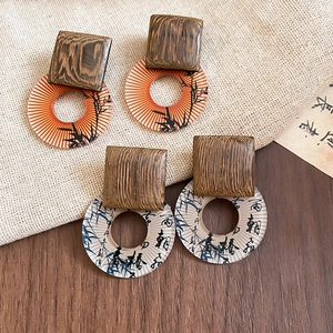 Detailed close-up of vintage square wood and resin pendant earrings with calligraphy art