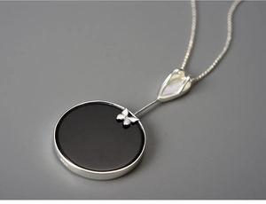 Macro shot of S925 sterling silver butterfly pendant with black disc and mother of pearl