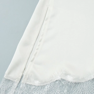 Close-up of white satin top featuring eyelash lace hem and side slit detail