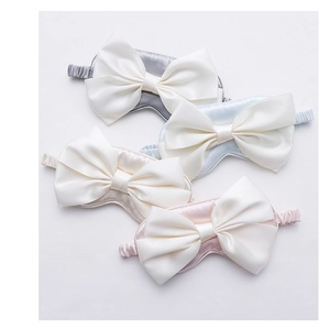 Macro shot of satin bow sleep masks in grey, light blue, beige, and pink colors