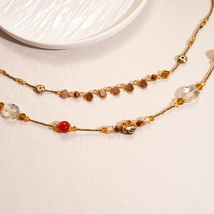 Macro detail of amber resin beads and floral metal accents on a vintage style necklace