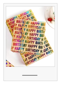Macro view of kraft paper gift wrap with holographic rainbow Happy Birthday foil lettering