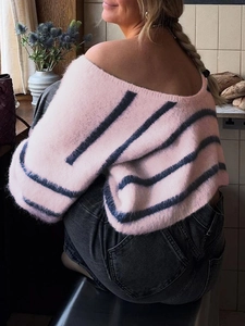 Detail of the soft fuzzy knit texture and pink-black stripes on an off-shoulder sweater