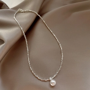 Elegant silver pearl necklace with cubic zirconia pendant on brown silk fabric background