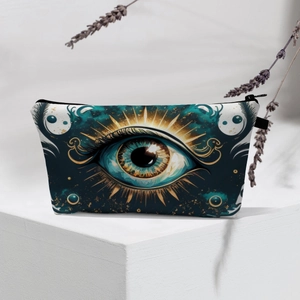Detail of waterproof Evil Eye makeup bag with gold embroidery on teal fabric texture