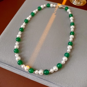 Dettaglio della collana di perle e agata verde con finiture in argento su vassoio morbido