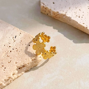 Macro shot of 18K gold plated stainless steel floral open ring on travertine stone