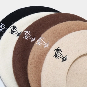 Detailed close-up of wool beret hats with delicate palm tree embroidery in various colors