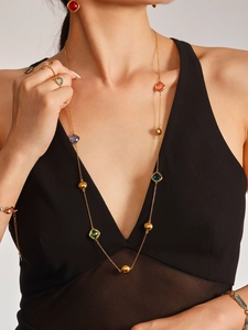 Mannequin portant un long collier doré avec pierres précieuses colorées et parure assortie