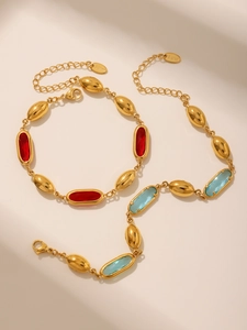 Nahaufnahme goldener Edelstahlarmbänder mit ovalen roten und blauen Kristallsteinen