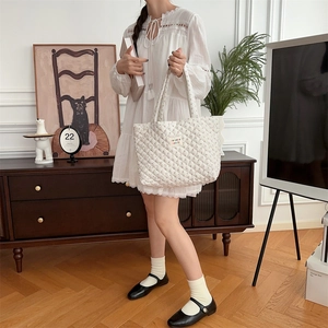 Detail of white quilted tote bag featuring delicate pink floral embroidery and soft fabric