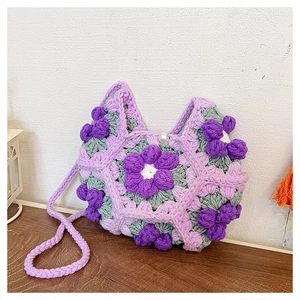 Detailed macro view of handmade crochet flower bag with pearl closure on wooden table