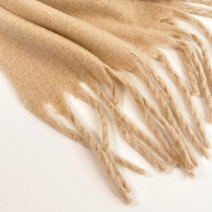 Close-up of beige mohair knit scarf showing texture and long tassel fringe details