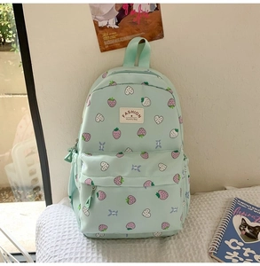 Close-up of mint green canvas backpack featuring cute purple strawberry prints