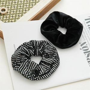 Detail of black velvet scrunchie and silver sequin hair tie on a decorative tray