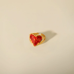 Detail view of adjustable gold open ring featuring a red heart embossed centerpiece